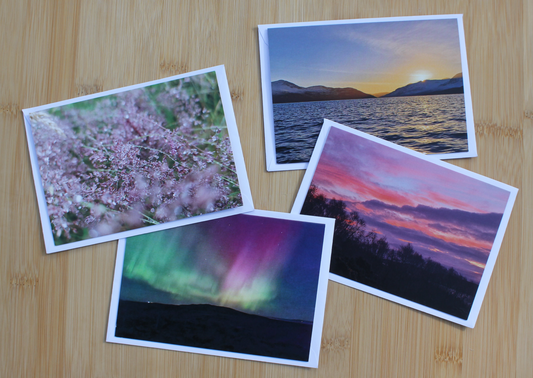 Four pack of Scottish Highlands Scenery Cards. Including the Northern Lights, a winter sunrise, evening sunset and dewy grasses.
